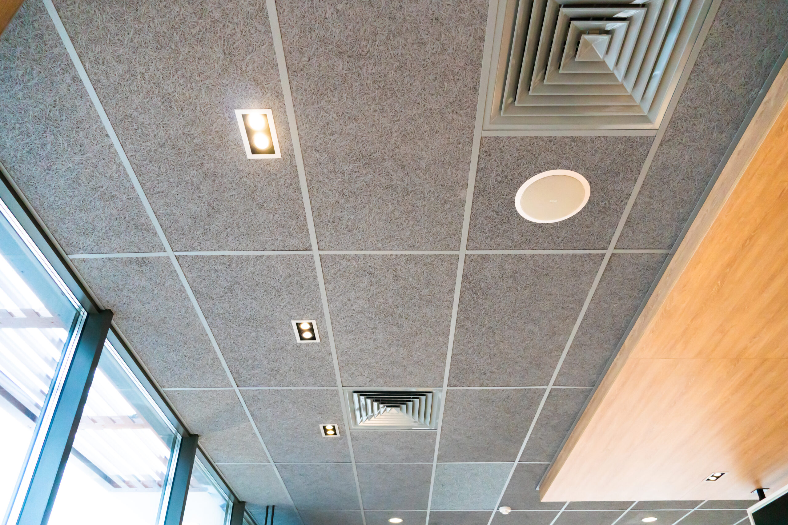 Suspended ceiling with ventilation holes and lamps. Interior design in a cafe or restaurant. Forced ventilation in a wall under the ceiling.